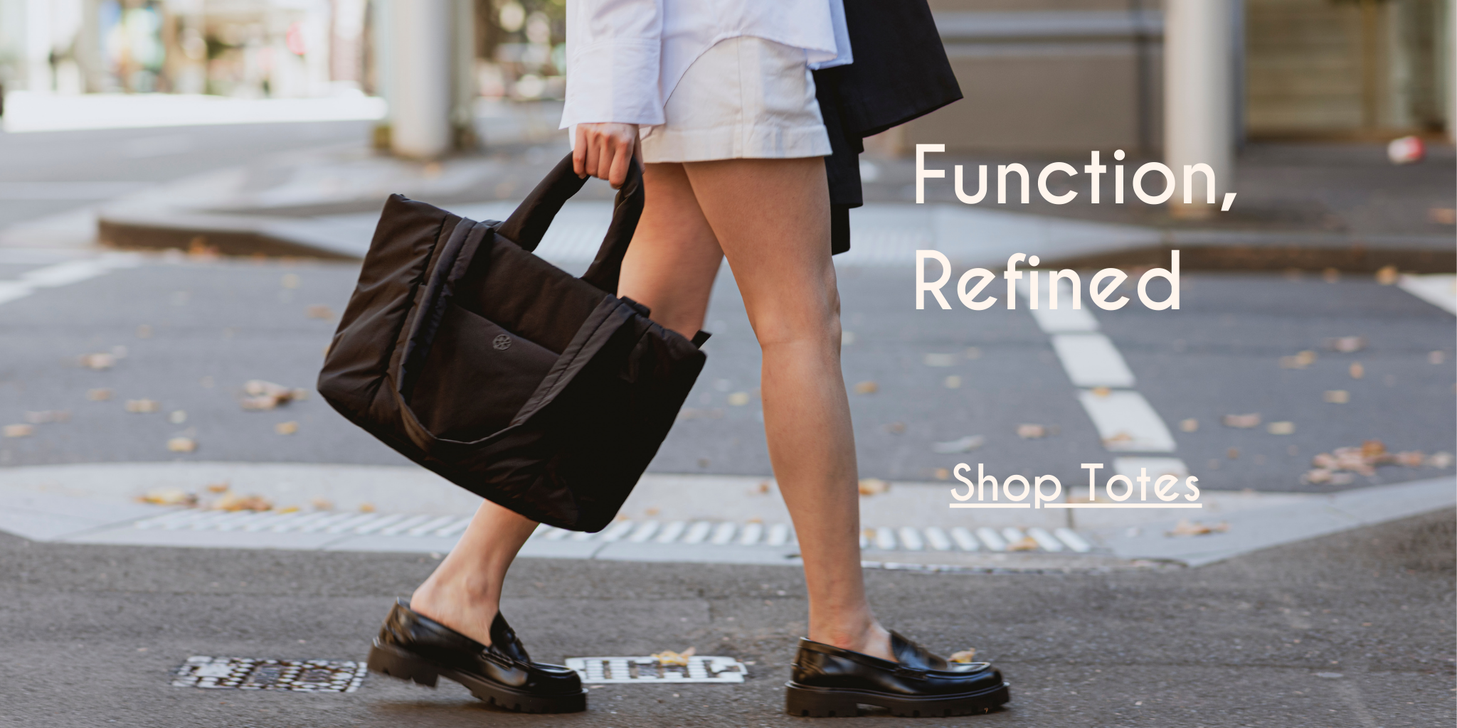 Woman walking on a street holding a brown tote bag with text 'Function, Refined Shop Totes'.